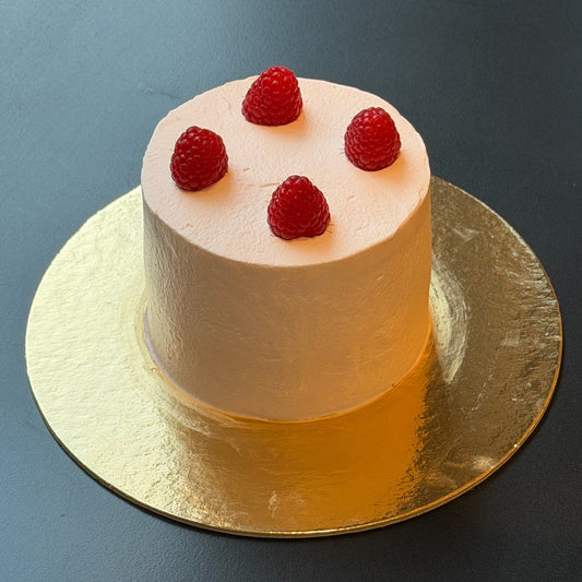 Raspberry rose mini cake with rose whipped cream, raspberry coulis, and fresh raspberries.
