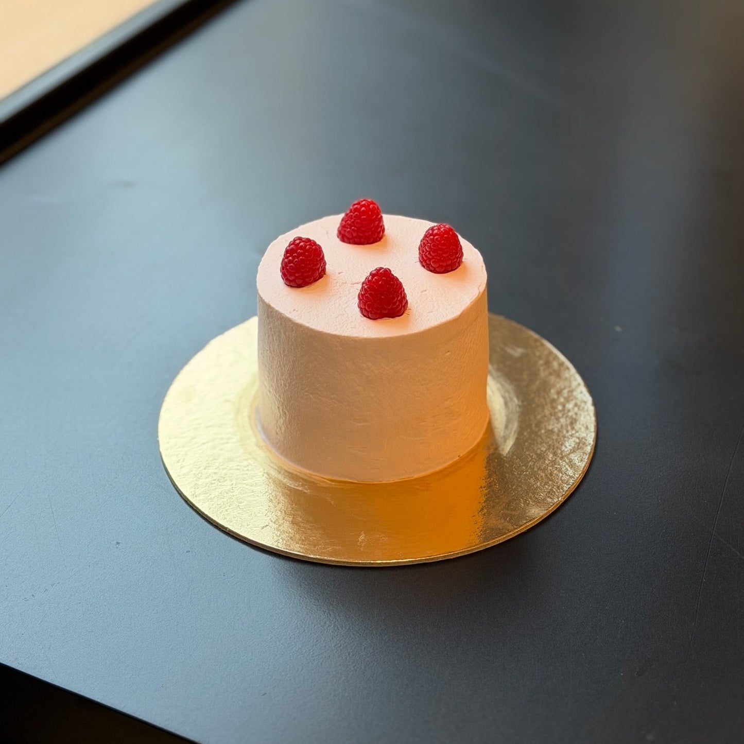 Raspberry rose mini cake with rose whipped cream, raspberry coulis, and fresh raspberries.