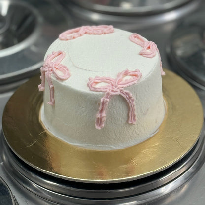 Cream bow mini cake covered in whipped cream and filled with strawberry or raspberry coulis.
