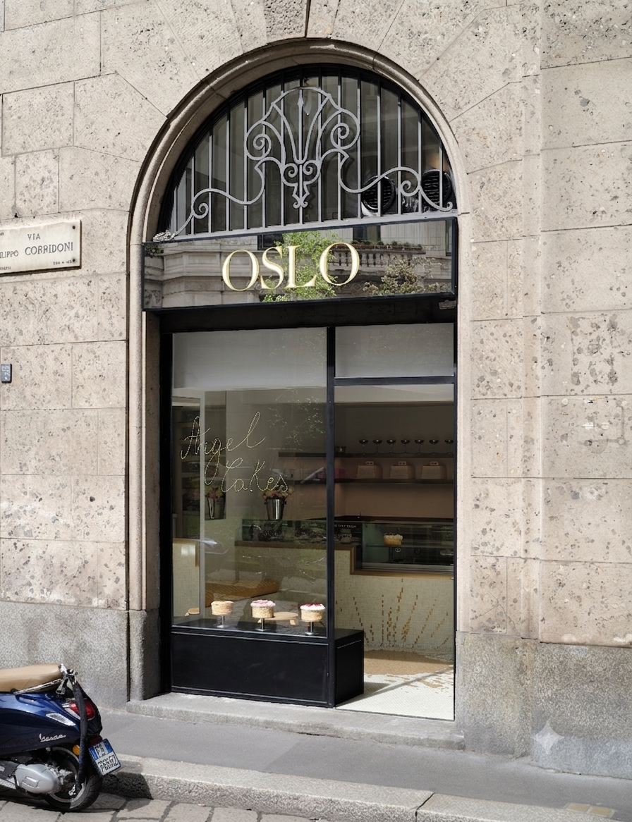 Oslo bakery storefront with a large arched window, black metal frame, and gold 'OSLO' lettering above the entrance, set against a stone building facade with a scooter parked at the lower left.